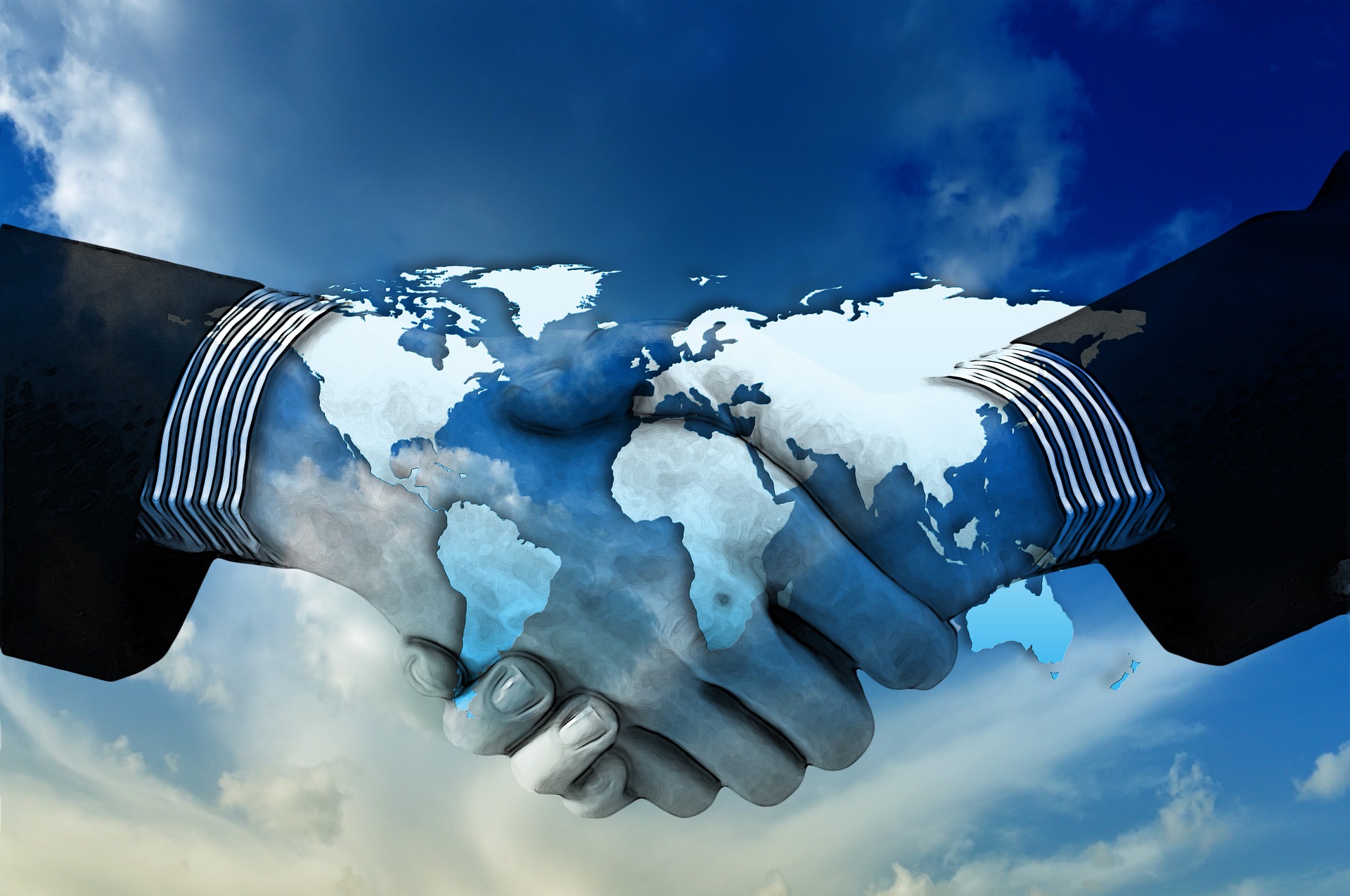 Hand squeech with superimposed world map Two people shaking hands with the image of the reflected world map, representing global agreements, unity and international cooperation.