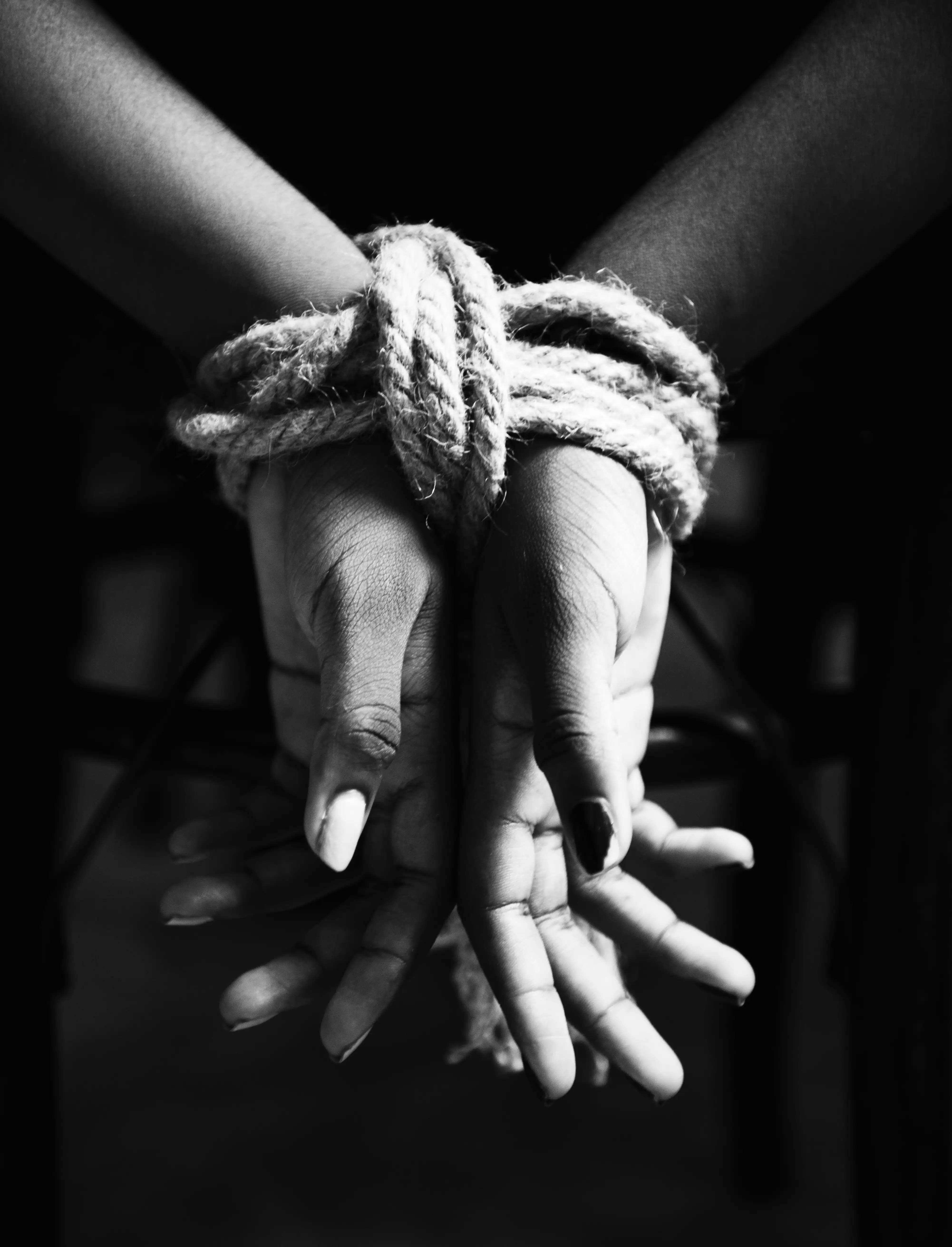 Hands Tied with Rope A close-up of hands bound with a thick rope, symbolizing oppression, kidnapping, or modern slavery.
